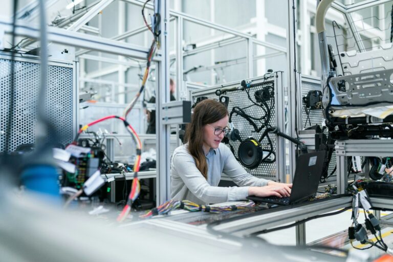Woman engineer working on a laptop in an industrial research and development facility.